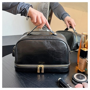 Detail view of double-layer black PU leather travel makeup bag with gold hardware