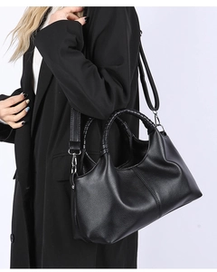 Detail of black pebbled leather tote featuring woven handles and a removable shoulder strap