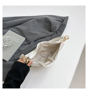 Detail of white dumpling bag showing beige fabric lining and gold hardware buckle