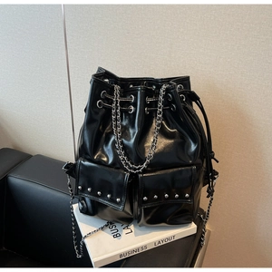 Detail of black glossy bucket bag with silver studs, drawstring closure and chain strap