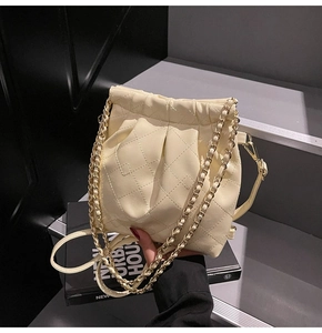 Detail of cream quilted leather bucket bag with gold chain and drawstring closure