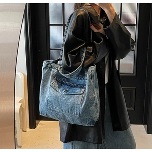 Detail of vintage blue denim tote bag with cargo pocket shown on a black leather coat