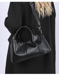 Detail of black pebbled leather tote bag with unique spiral woven handle and silver hardware