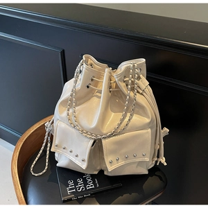 Detail view of cream white bucket bag with silver rivet pockets and chain strap