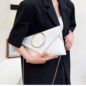 Détail de la pochette enveloppe blanche avec poignée ronde dorée et fine chaîne élégante