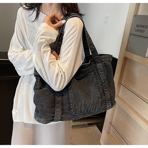 Detail of the washed denim tote bag showing distressed texture and large front pocket