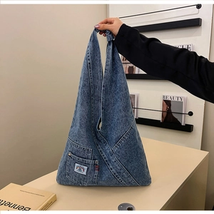 Detail of blue washed denim handbag with decorative pocket and red stitching detail