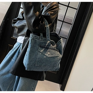 Detail of vintage blue washed denim tote bag showing metal buckle and fabric texture