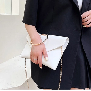 Détail d'une pochette enveloppe blanche avec anneau doré et chaîne sur un costume noir