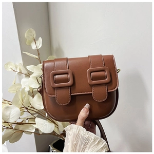 Détail d'un sac besace marron vintage avec boucles doubles et texture en similicuir
