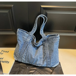 Close-up of vintage washed denim tote bag showing texture and front pocket detail