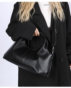 Detail of black lychee leather handbag featuring a braided handle and shoulder strap