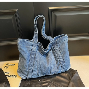 Close-up of blue denim tote bag texture with large front pocket and double straps