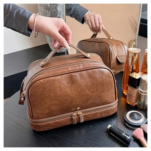 Close-up of brown vintage leather makeup bag with dual-layer zippers and golden hardware