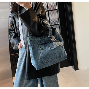 Close-up of vintage blue denim tote bag with cargo pocket and silver metal button detail