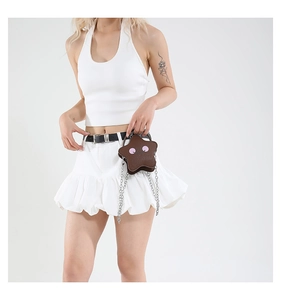 Brown star-shaped crossbody bag with pink accents styled on a model in a trendy outfit