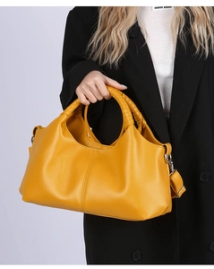 Detail of yellow leather tote bag featuring woven handle and detachable shoulder strap