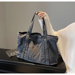 Close-up of washed gray denim tote bag with reinforced handles and large front pocket