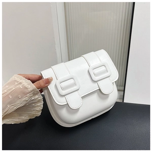Détail du sac besace en cuir blanc avec boucles décoratives et coutures précises