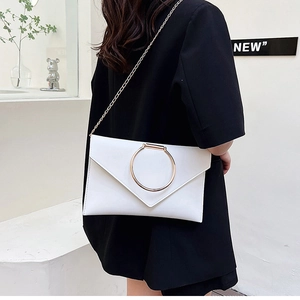 Pochette enveloppe en cuir blanc avec boucle anneau doré et chaîne portée par le modèle
