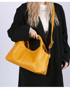 Detail of yellow pebbled leather handbag with braided handle and silver metal hardware