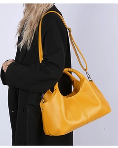 Detail view of yellow lychee grain tote bag with adjustable strap on black coat