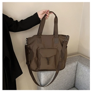 Detail of dark brown nylon tote bag with metal chain pocket and adjustable strap