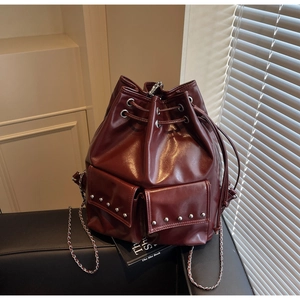Detail view of burgundy bucket bag with silver studs, chain strap and drawstring closure