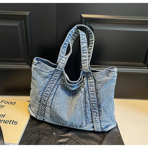 Detail of blue denim tote bag showing sturdy texture and functional front pocket