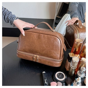 Detail view of large brown faux leather cosmetic bag with dual zipper and top handle