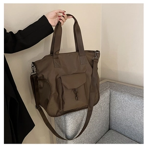 Detailed view of brown nylon tote bag featuring adjustable strap and front pocket