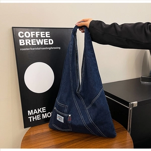 Detailed view of dark blue denim tote bag featuring decorative pocket and patch