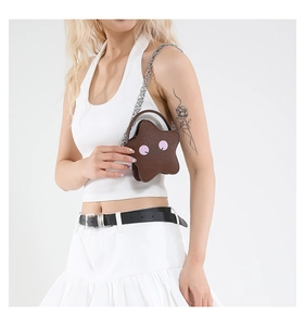 Detail shot of a brown star-shaped crossbody bag with a smile face worn by a model