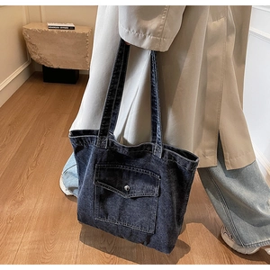 Detail of vintage blue denim tote bag with front snap pocket and dual shoulder straps