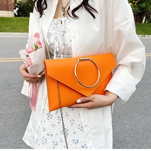 Détail de la pochette enveloppe orange vif avec anneau argenté et bandoulière en chaîne