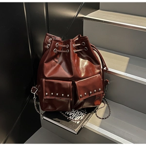 Detail of dark brown glossy leather bucket backpack with silver rivets and drawstring