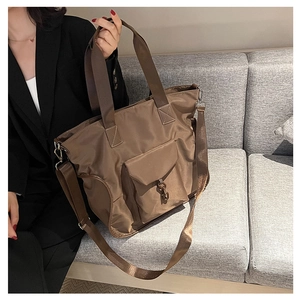 Detail of coffee brown nylon tote bag featuring front buckle pocket and textured fabric