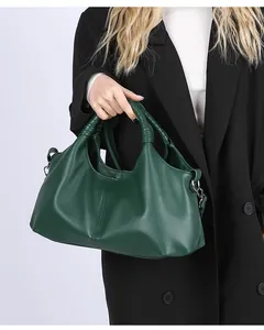 Detail of dark green pebble leather tote bag with unique woven handles and metal hooks