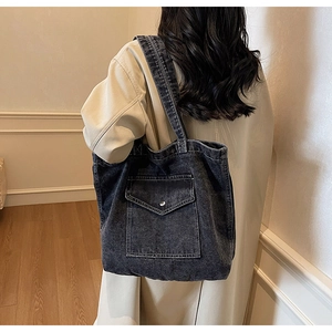 Detailed view of the dark denim tote bag with functional front flap pocket and silver buckle