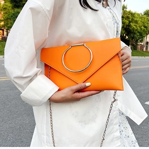 Détail de la pochette enveloppe orange avec grand anneau argenté et bandoulière chaîne