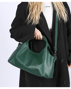 Macro detail of dark green lychee leather handbag with woven handle and silver hardware