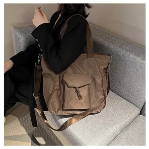 Detail of waterproof nylon tote bag with front pocket and chain decoration in dark coffee