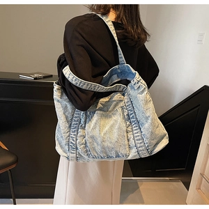 Detail of light blue denim tote bag with vertical stitching and wide shoulder strap