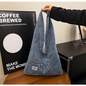 Detail of vintage blue denim tote bag featuring a round logo patch and durable texture