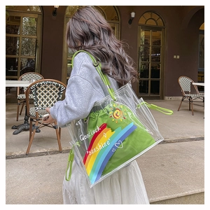 Detail of transparent PVC tote bag with green drawstring inner pouch and rainbow art print
