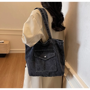 Detail view of black vintage denim tote bag with metal buckle flap pocket and large capacity