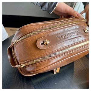 Detail of vintage brown leather toiletry bag featuring dual metal zippers and side handle