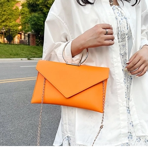Vue détaillée de la pochette enveloppe orange vif avec anneau doré et bandoulière
