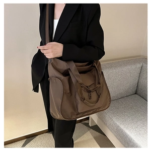 Detail of a large brown nylon tote bag with wide strap on a model for daily use
