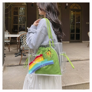 Detail of transparent PVC beach bag with green drawstring pouch and rainbow embroidery